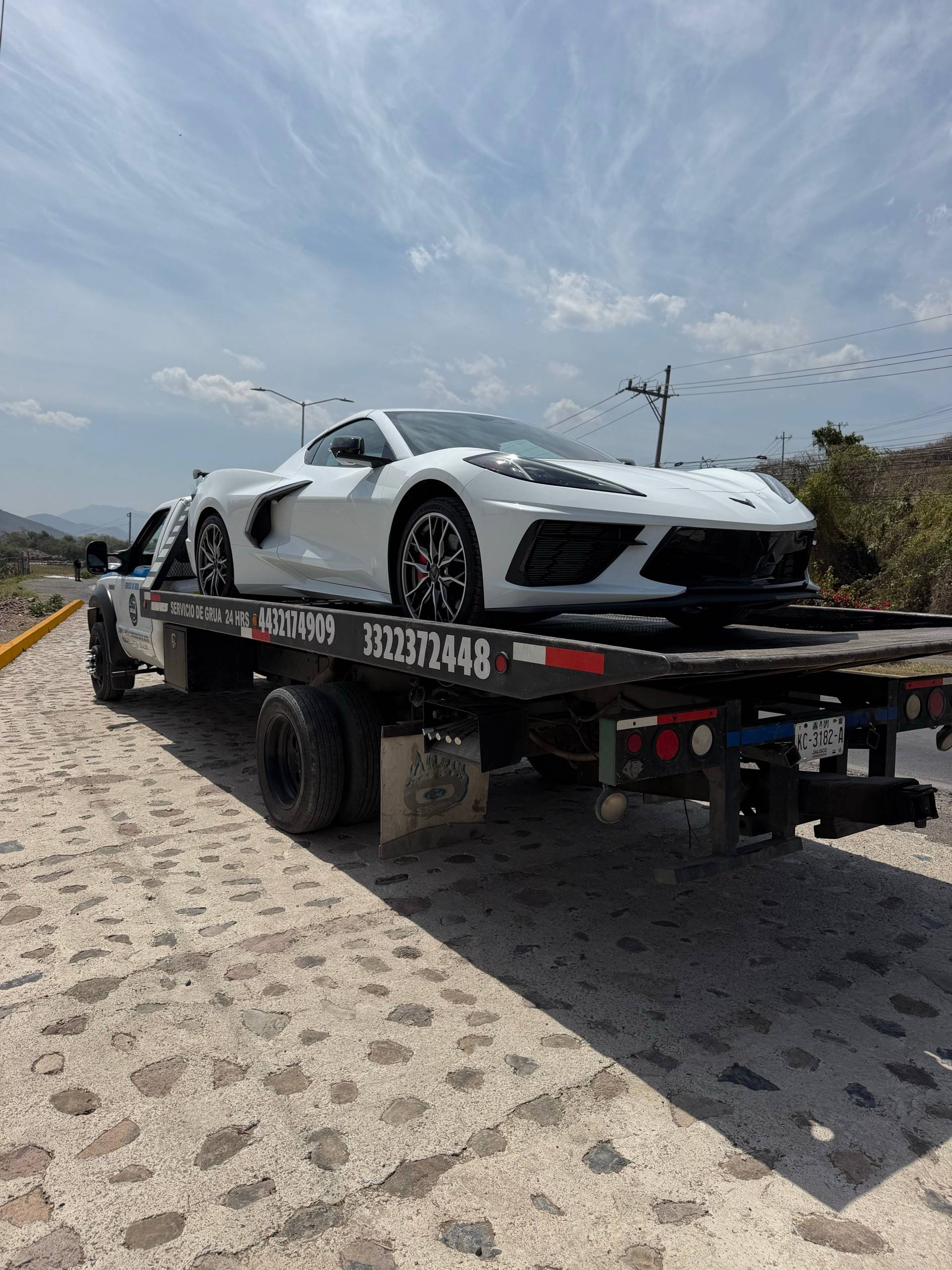 Corvette C8 blanco amarrado sobre la plataforma de Grúas Élite, en carretera cerca de Guadalajara
