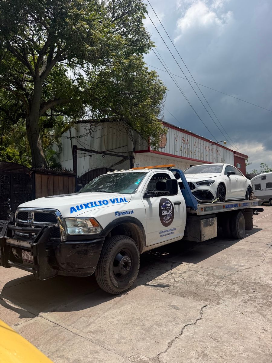 Grúa Élite con rótulo de auxilio vial cargando un Mercedes-Benz